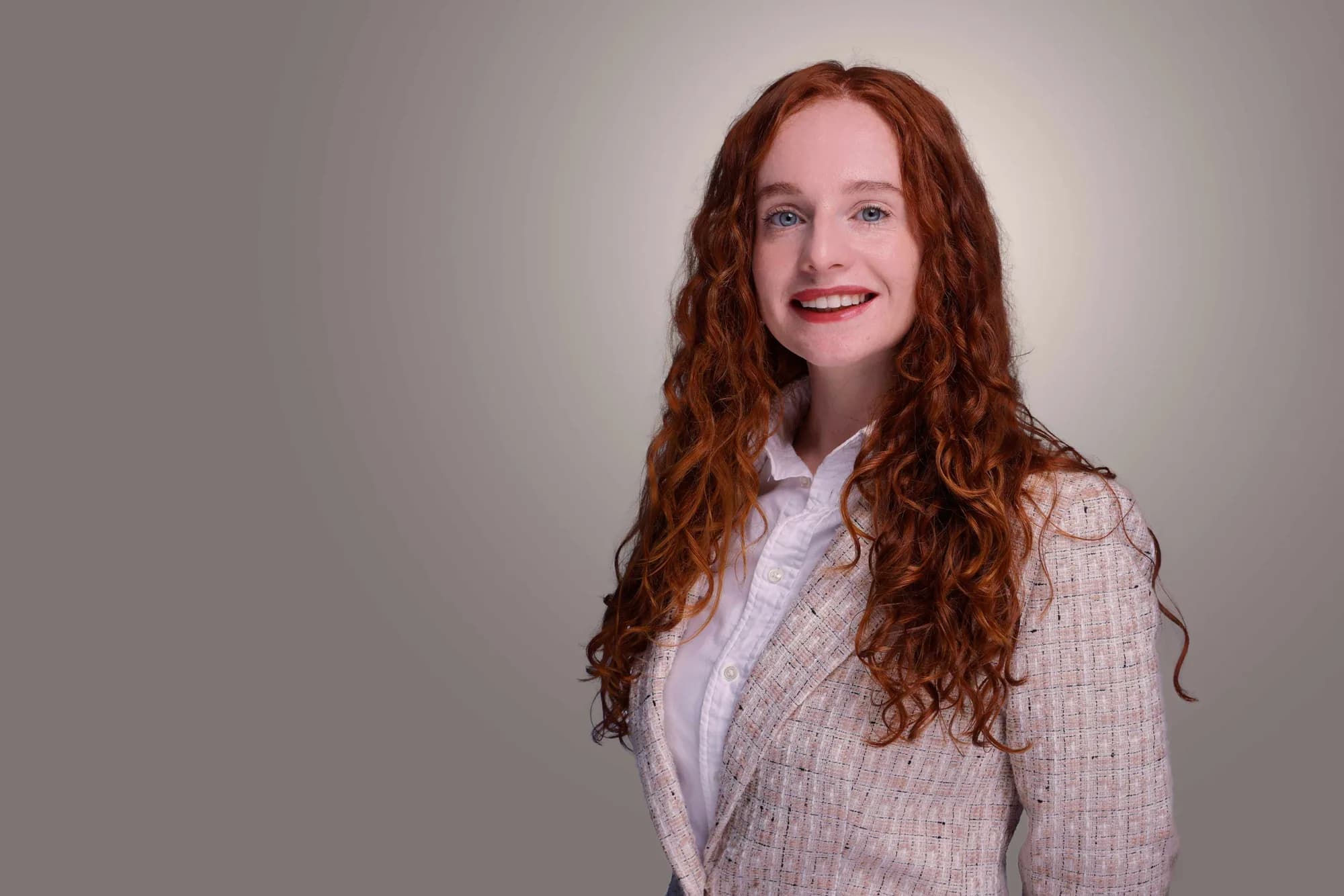 Corporate portrait of a woman with auburn hair on a soft grey backdrop, Sydney