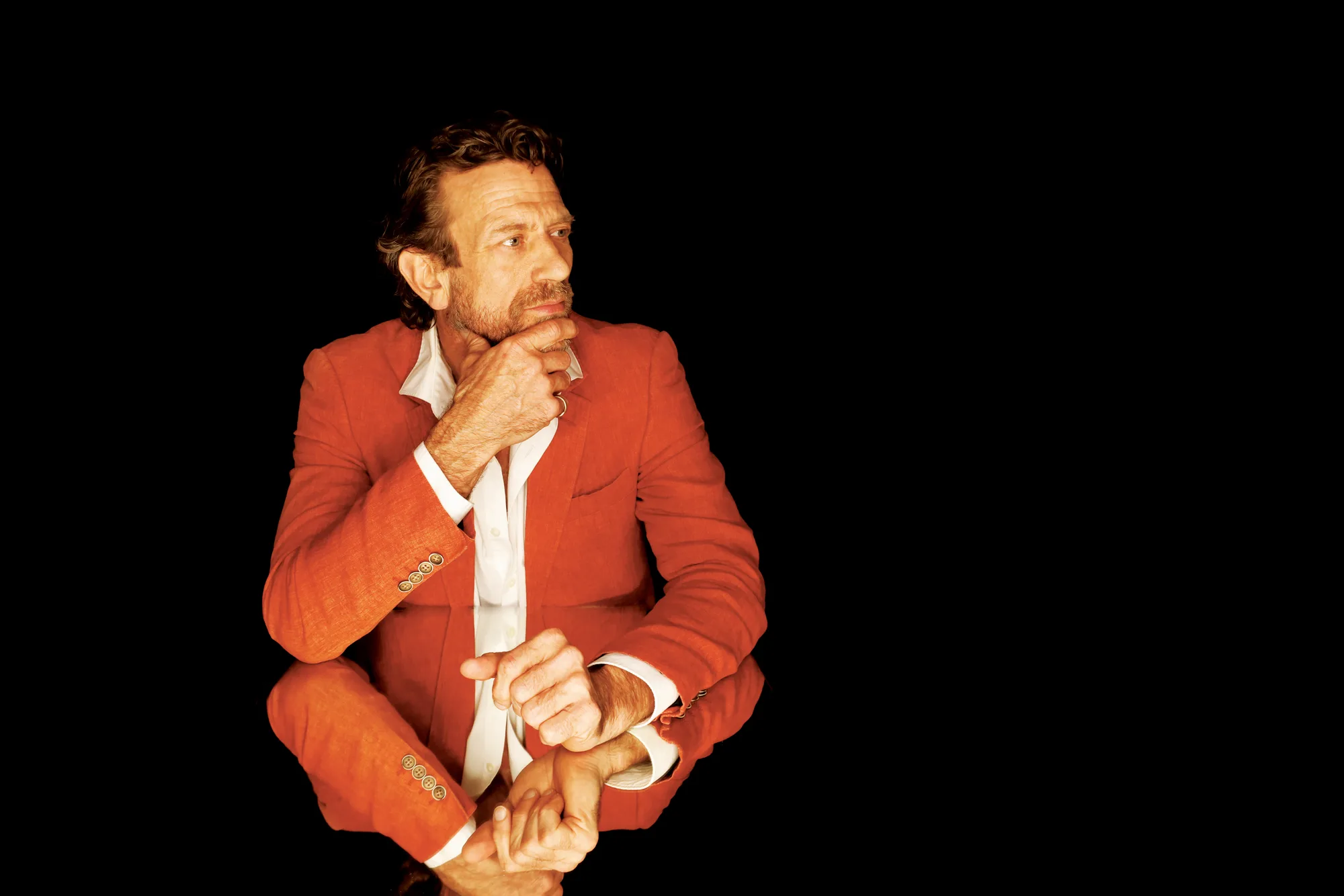 Editorial portrait of a man in a red jacket on a black background, Sydney
